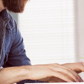 Bearded man typing on computer